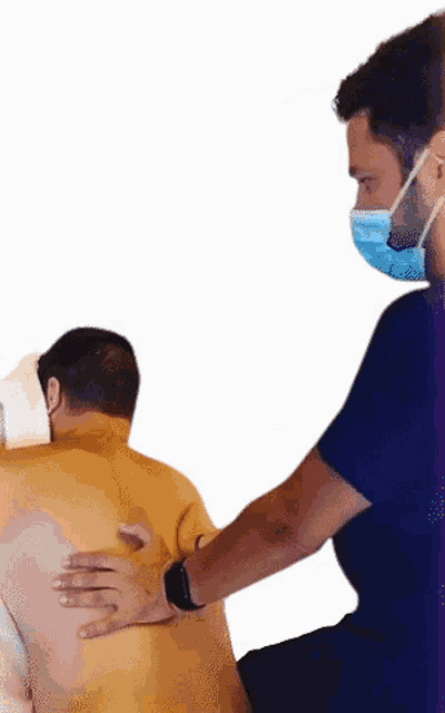 a man wearing a face mask is giving a man a massage