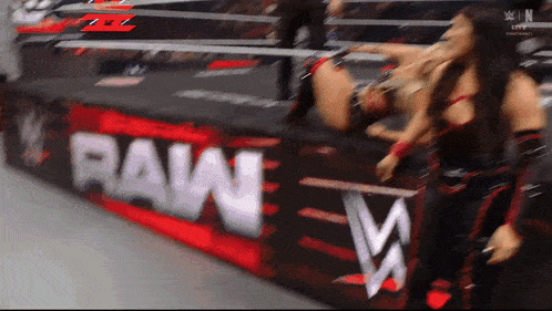 two women wrestling in front of a raw banner