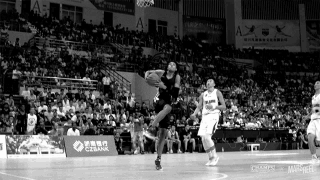 a black and white photo of a basketball game with a czbank ad in the background