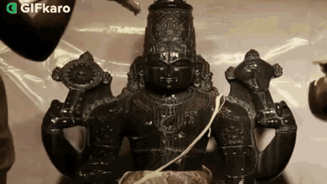 a statue of a deity with a gifkaro logo in the lower right corner