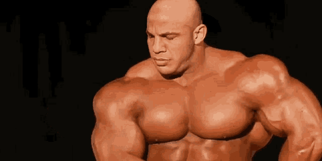 a bald man is flexing his muscles in a close up of his arm .