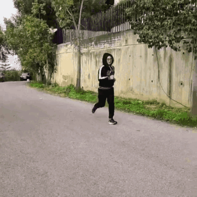 a person is running down a road with a fence in the background