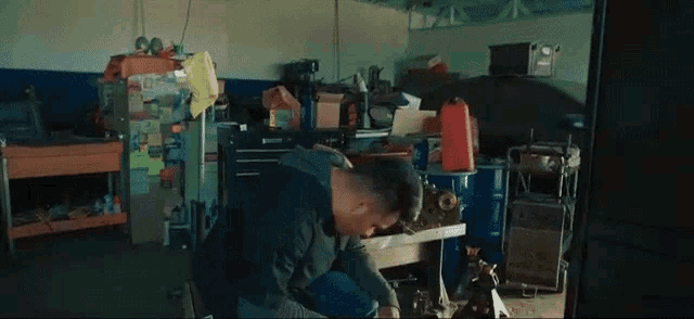 a man sits in a messy garage with his hands on his face