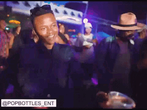 a man in a hat is dancing in a crowd with the words popbottles ent below him