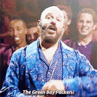 a man in a blue robe is singing about the green bay packers