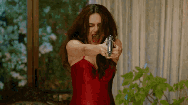 a woman in a red dress is holding a gun