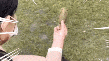 a person wearing a mask is holding a pickle in their hand