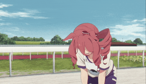 a girl with red hair is standing on a track with a white fence in the background