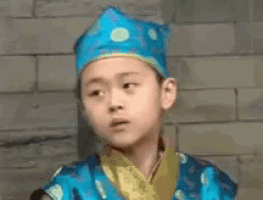 a young boy is wearing a blue hat and a blue and yellow outfit .