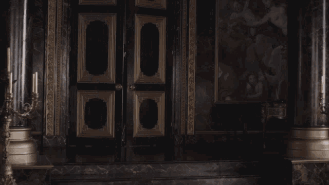 a dark room with a painting on the wall and candles on the floor