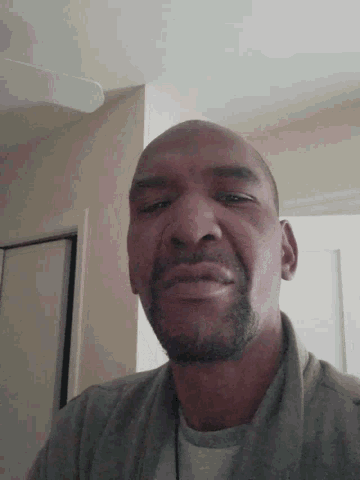 a man with a beard and a gray shirt looks down at the camera