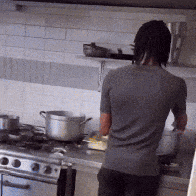 a man in a gray shirt is cooking on a stove
