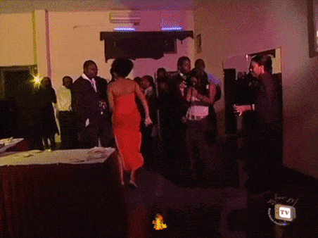 a woman in a red dress is dancing in a room with a tv behind her