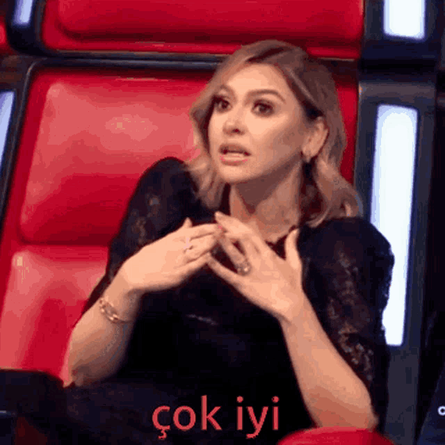 a woman in a black dress is sitting in a red chair with the words " çok iyi " written on the bottom