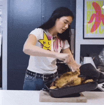 a woman in a white shirt with a smiley face is cooking a chicken