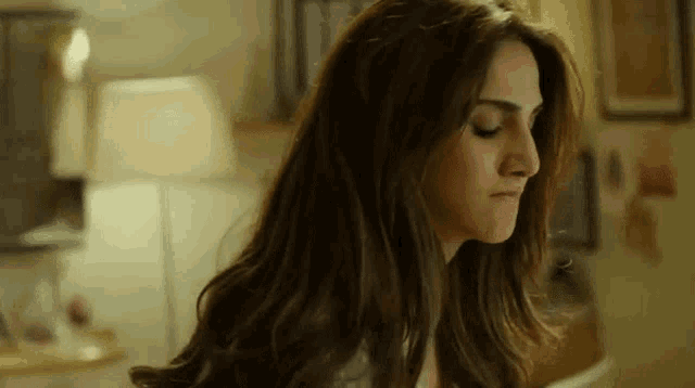 a woman with long brown hair is making a funny face in a room .