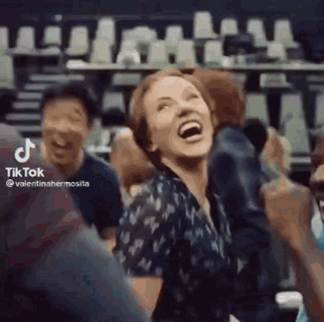 a woman is laughing in front of a crowd of people .