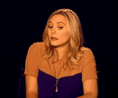 a woman in a purple top and brown shirt is making a funny face