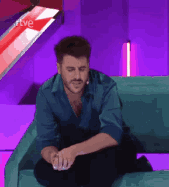 a man is sitting on a couch in front of a sign that says " rtve "