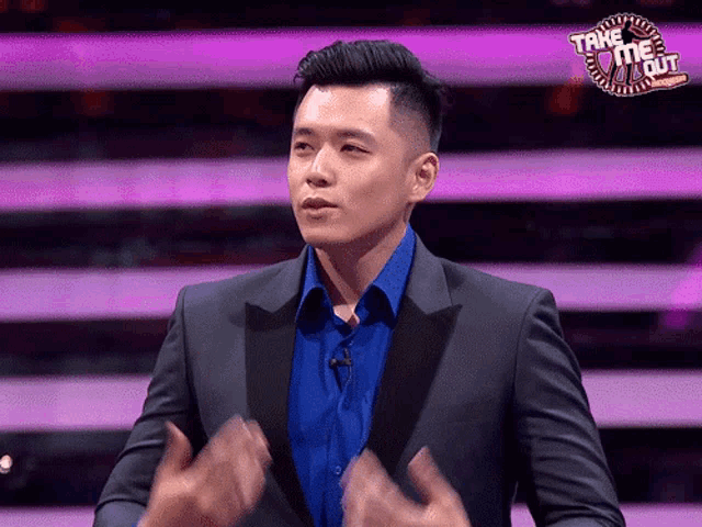 a man in a suit and blue shirt is standing in front of a sign that says take me out