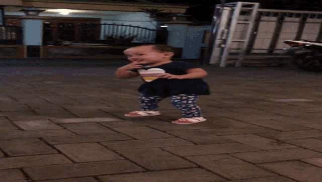 a little girl wearing a heart shaped shirt is standing on a brick sidewalk