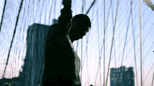 a silhouette of a person standing on a bridge with their arms outstretched
