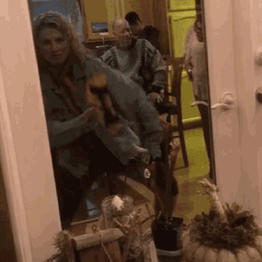 a group of people are sitting in a hallway with a pumpkin on the floor