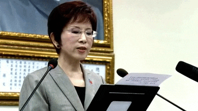 a woman in a suit is reading a piece of paper
