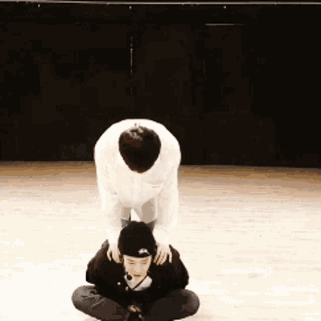a man in a white shirt is kneeling down next to another man