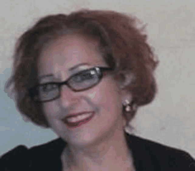 a woman wearing glasses and a black jacket is smiling .