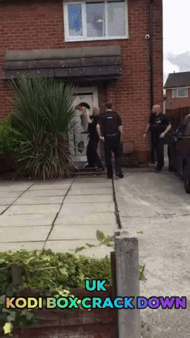 a group of police officers are standing in front of a brick house with the words uk kodi box crack down above them