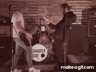 a man playing a guitar in front of a sharper side drum set