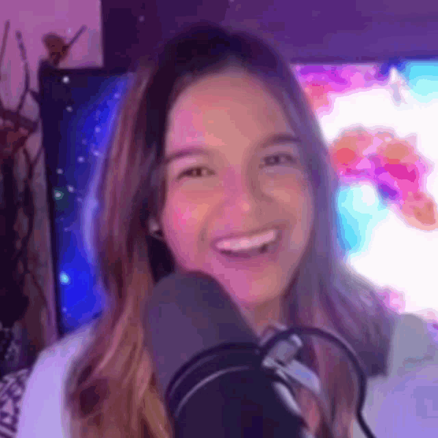 a woman is smiling in front of a microphone while sitting in front of a television .