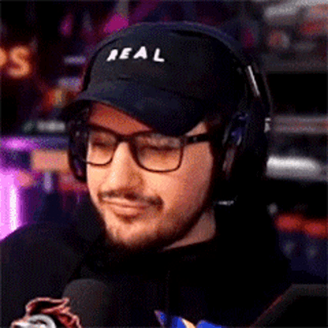 a man wearing headphones and a hat that says real on it