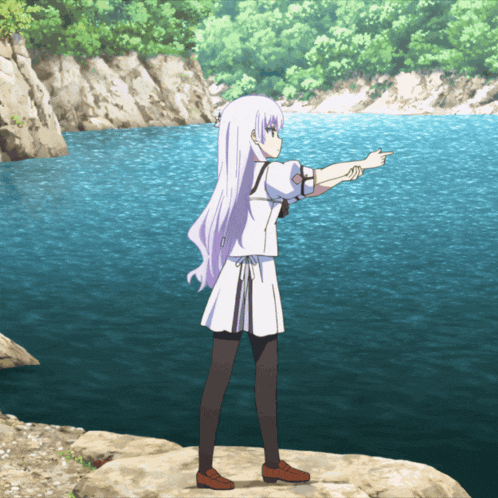 a girl in a white dress is standing on a rock pointing at the water