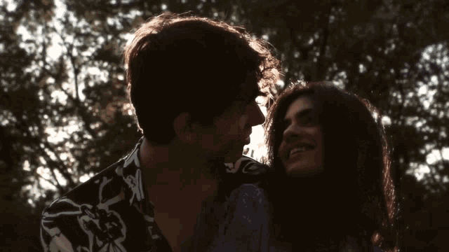 a man in a black and white shirt kisses a woman on the cheek
