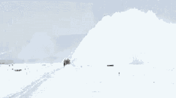 a snow blower is blowing snow on a snow covered road
