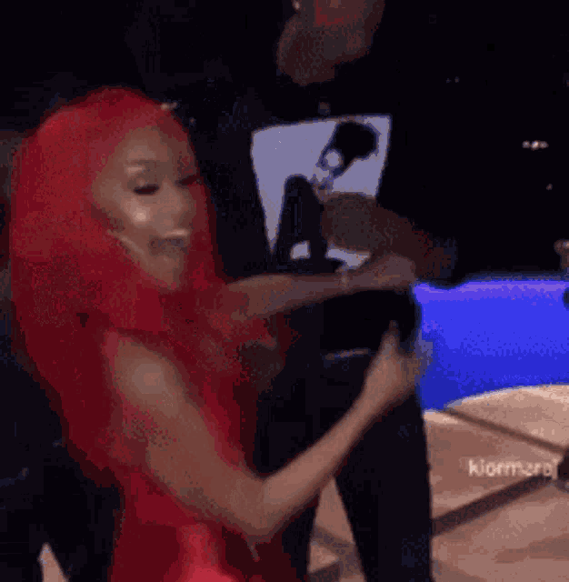 a woman in a red dress is dancing in a club with a man .