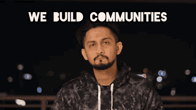 a man with a beard stands in front of a sign that says " we build communities "