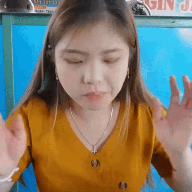 a young woman in a yellow shirt is making a funny face .