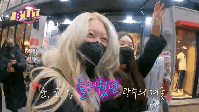 two women wearing face masks are standing in front of a store that says blitz