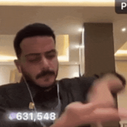 a man with a beard and mustache is wearing headphones and looking at his watch .