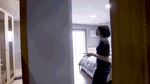 a woman is standing in a bedroom looking out a doorway