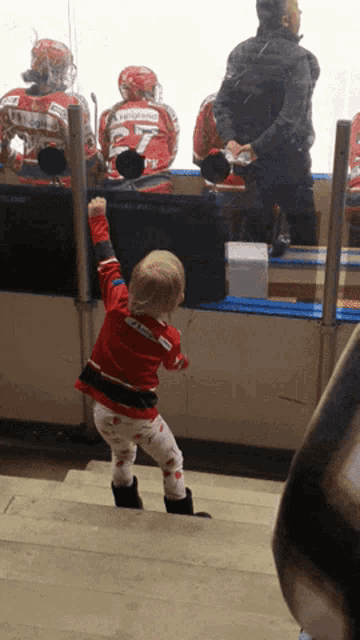 a little girl wearing a red jersey with the number 25 on the back