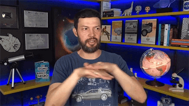a man with a beard is standing in front of a shelf with a globe on it .