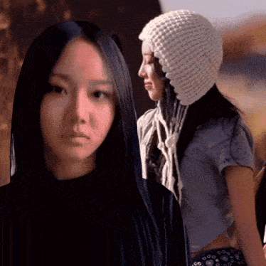 a woman with long black hair wearing a knitted hat