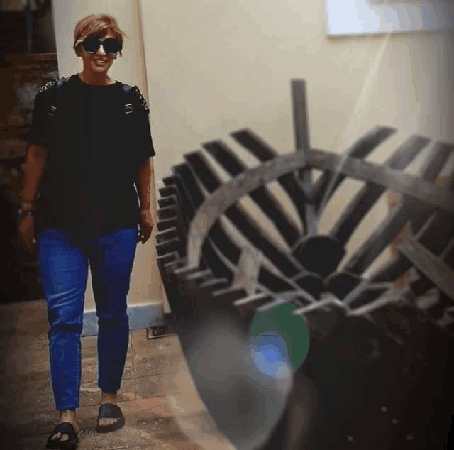 a woman wearing sunglasses and a black shirt stands in front of a wheel