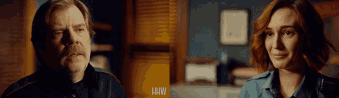 a man with a mustache and a woman with red hair are sitting next to each other in a dark room