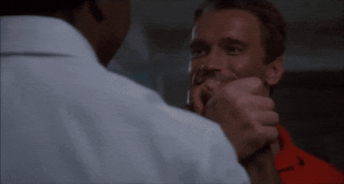 a man in a white shirt is holding another man 's neck