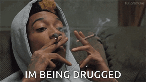 a man in a hoodie is smoking a cigarette and saying `` i 'm being drugged '' .